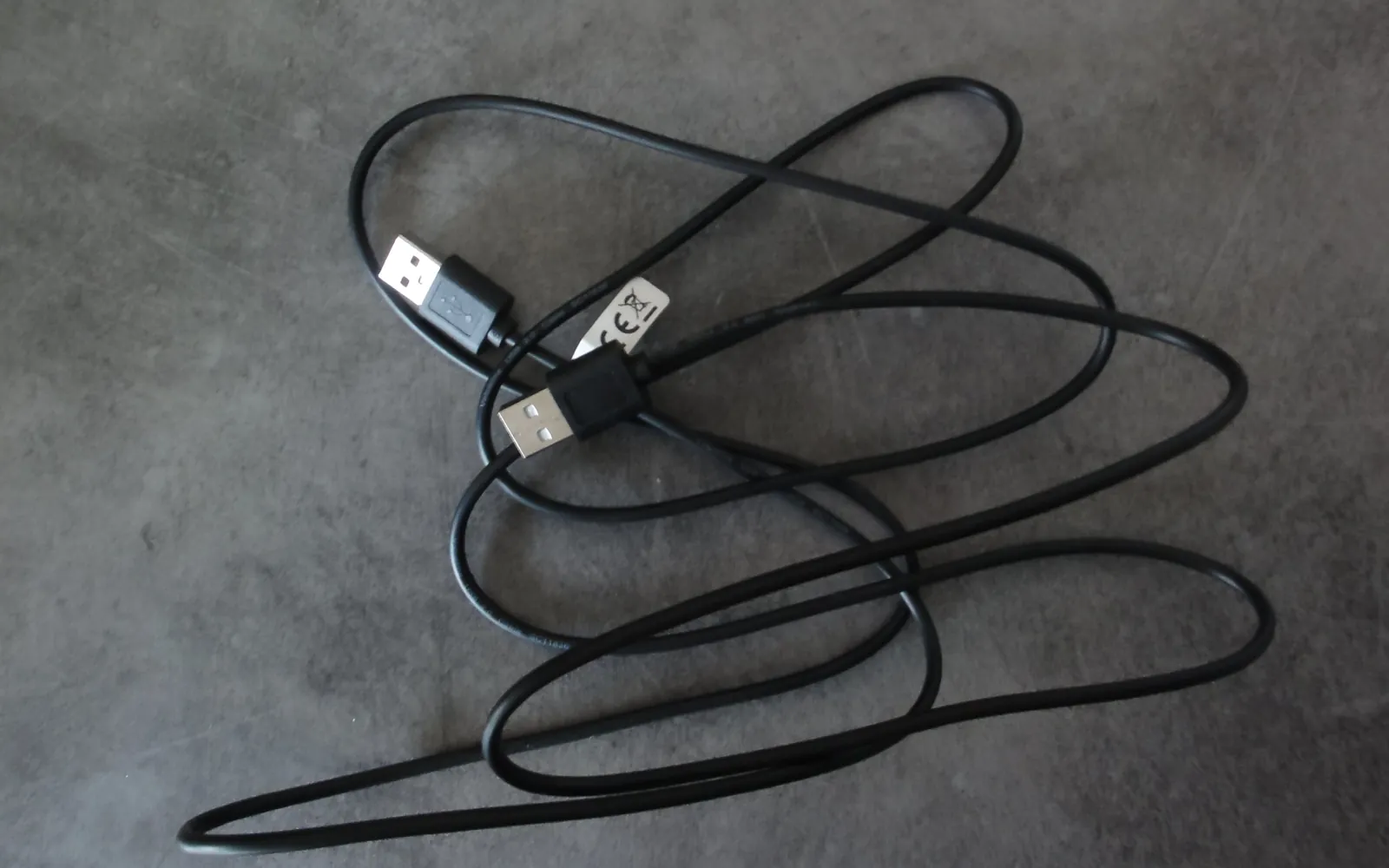 A black USB cable coiled on a grey surface